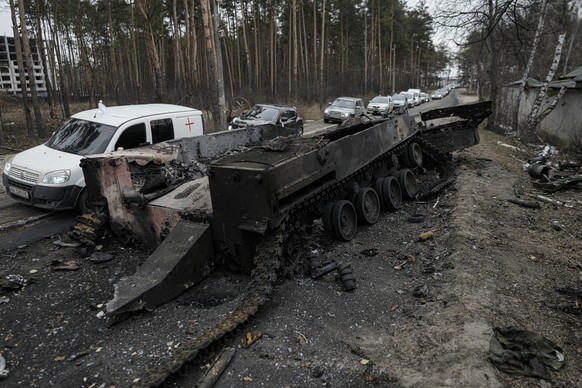 Cars drive past a destroyed Russian tank as a convoy of vehicles evacuating civilians leaves Irpin, on the outskirts of Kyiv, Ukraine, Wednesday, March 9, 2022. A Russian airstrike devastated a matern ...