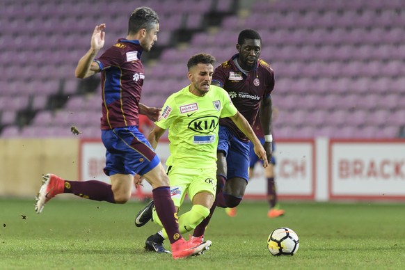 Le joueur Argovien Varol Tasar, centre, est a la lutte pour le ballon avec deux joueurs Genevois William Le Pogam, gauche, et Christopher Mfuyi, droite, lors de la rencontre de football du Championnat ...