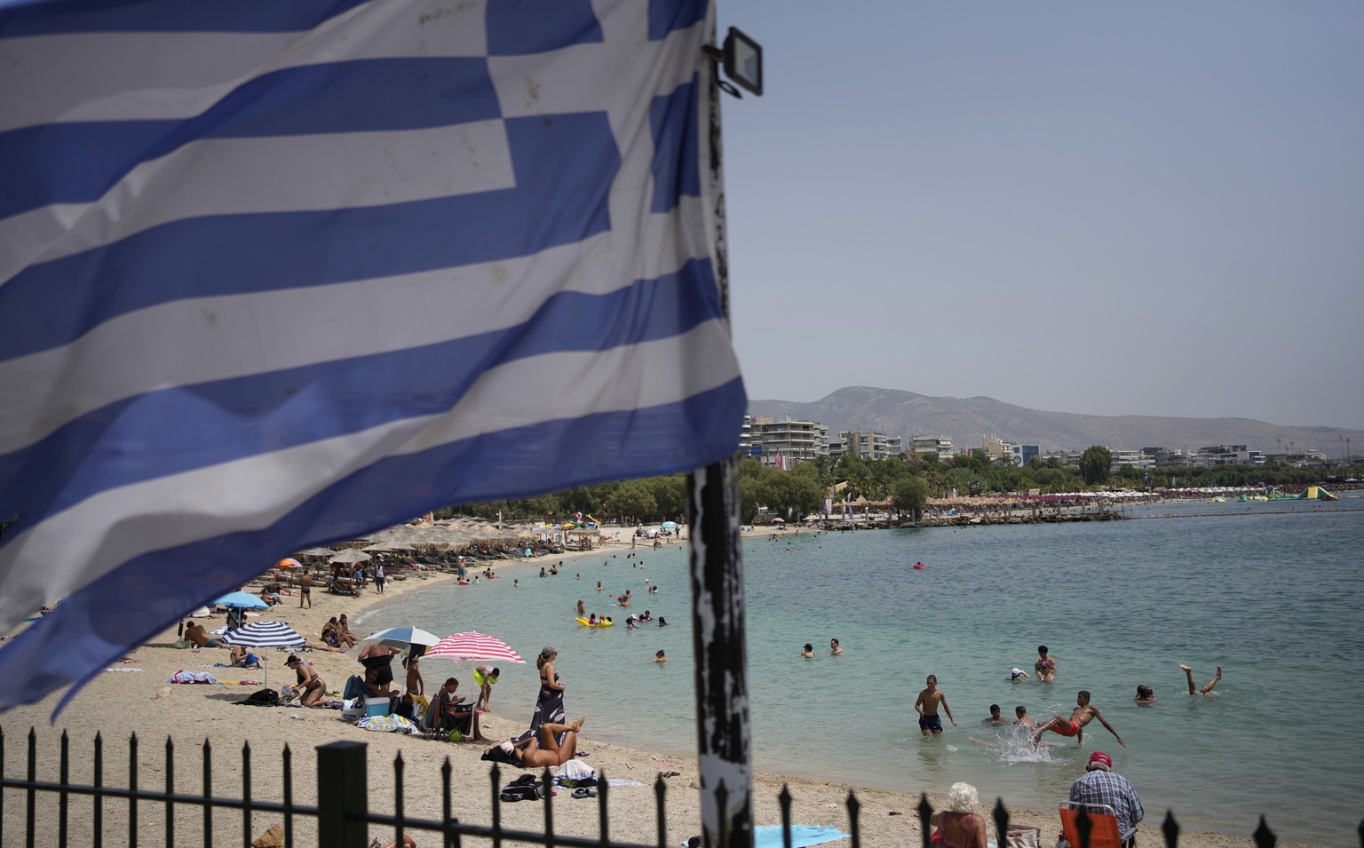 People enjoy the sea as a Greek flag waves at Alimos beach, in southern Athens, Greece, on Wednesday, July 26, 2023. A third successive heat wave has struck Greece, with the temperature in many parts  ...