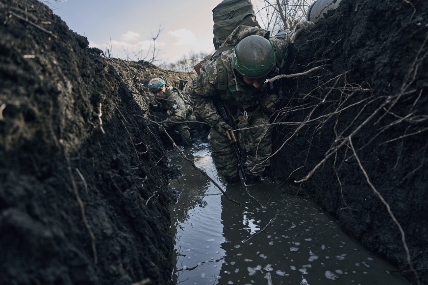 Ukrainian soldiers in a trench under Russian shelling on the frontline close to Bakhmut, Donetsk region, Ukraine, Sunday, March 5, 2023. (AP Photo/Libkos)