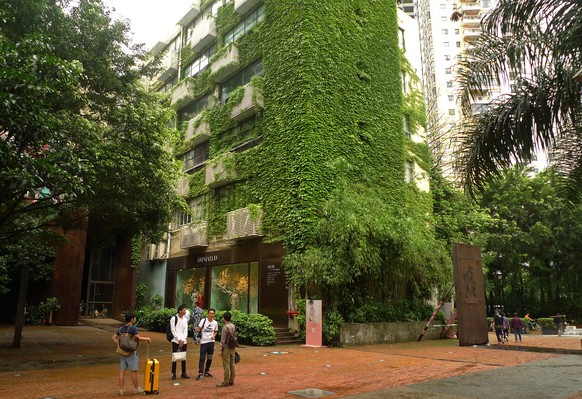 In this Friday, April 22, 2016 photo, people stand in front of an ivy-clad building in the art and design zone OCT Loft in Shenzhen, China. For business travelers to the southern Chinese manufacturing ...