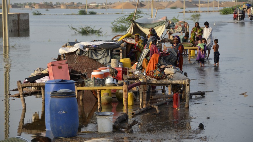 FILE - Families sit near their belongings surrounded by floodwaters, in Sohbat Pur city of Jaffarabad, a district of Pakistan's southwestern Baluchistan province, Aug. 28, 2022. The flooding has ...