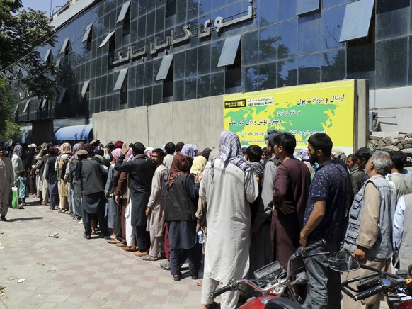 Afghans wait in front of Kabul Bank, in Kabul, Afghanistan, Wednesday, 25. 15, 2021. The Taliban wrested back control of Afghanistan nearly 20 years after they were ousted in a U.S.-led invasion follo ...