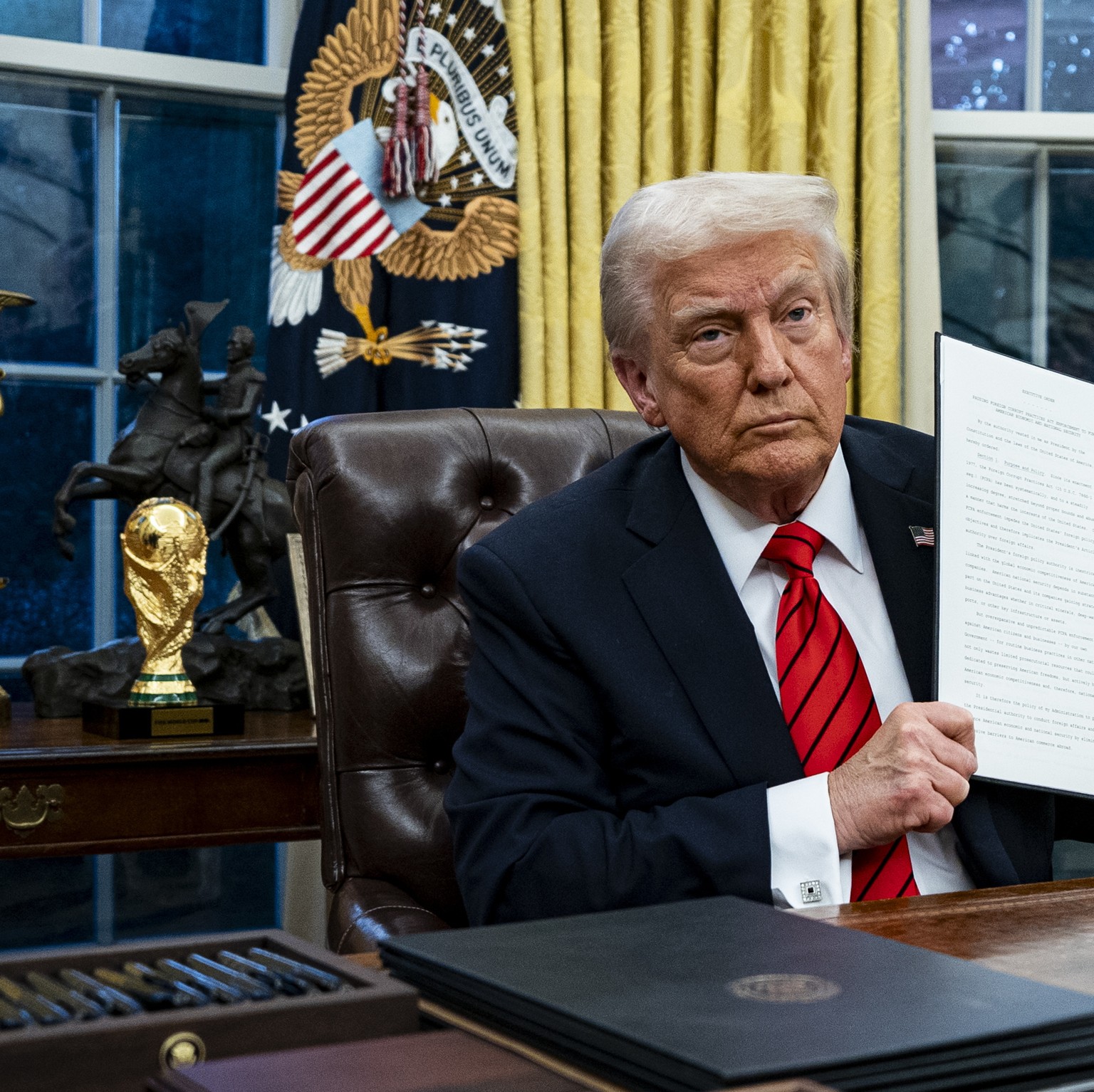 epa11887155 US President Donald Trump displays an executive order as Howard Lutnick (R), chief executive officer of Cantor Fitzgerald LP and US commerce secretary nominee, watches in the Oval Office o ...