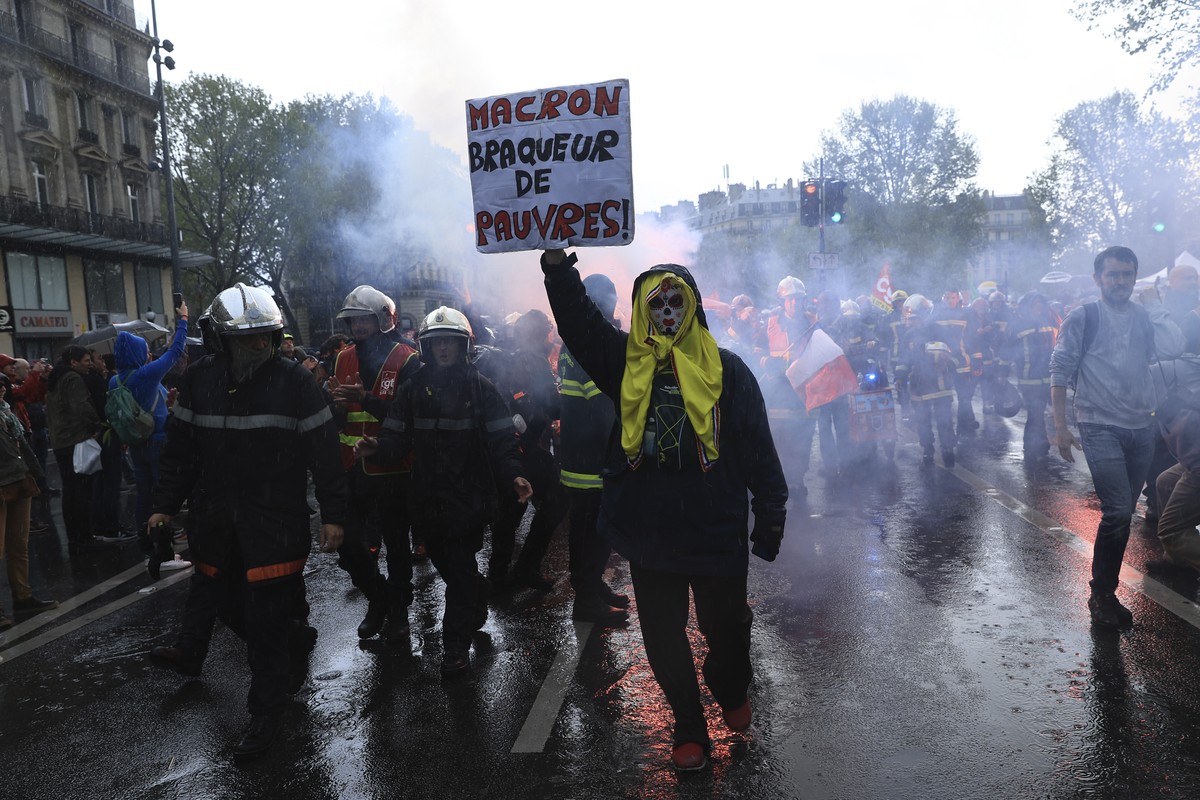 Rescue workers and a protester holding a placard reading "Macron, robber of the poor" march during a demonstration, Monday, May 1, 2023 in Paris. French unions plan massive demonstrations ar ...