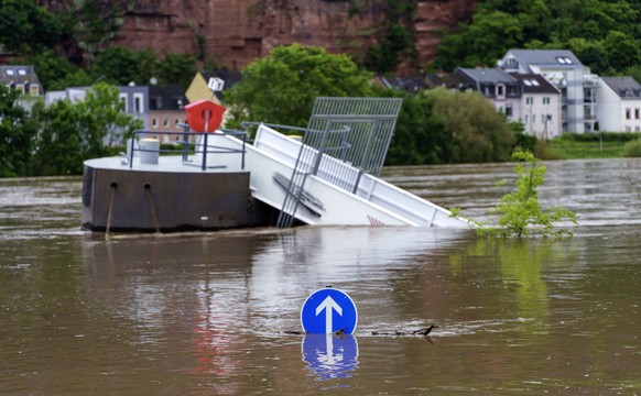 18.05.2024, Rheinland-Pfalz, Trier: Ein Verkehrs-Schild und ein Schiffsanleger stehen am Zurlaubener Ufer im Moselhochwasser. F