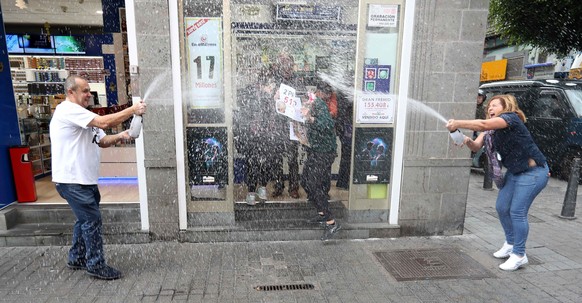 epa06402717 Workers of a lottery shop celebrate after selling the third prize of El Gordo (The Fat One) lottery in Las Palmas, Canary Islands, Spain, 22 December 2017. The traditional Spanish Christma ...