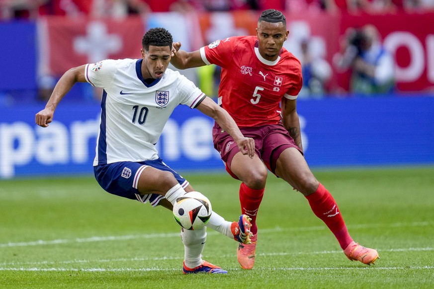 England&#039;s Jude Bellingham, left, and Switzerland&#039;s Manuel Akanji challenge for the ball during a quarterfinal match between England and Switzerland at the Euro 2024 soccer tournament in Dues ...