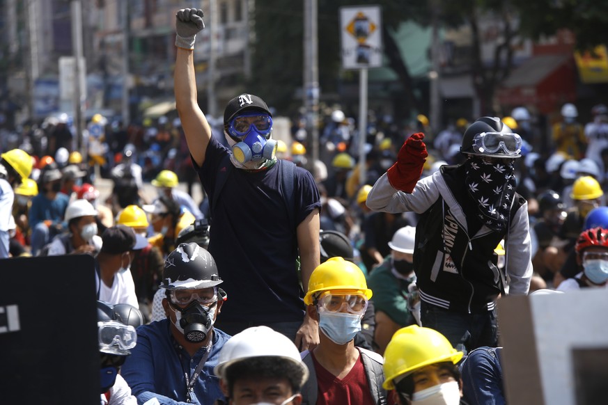 Protesters take positions behind a makeshift barricade as armed riot policemen gather in Yangon, Myanmar, Monday, March 8, 2021. Myanmar security forces continued to clamp down on anti-coup protesters ...