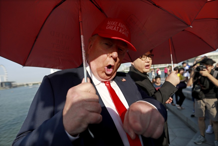 epa06792878 Donald Trump impersonator Dennis Alan (L) gestures as Kim Jong-Un impersonator Howard X (C) speaks to members of the media at the Merlion Park in Singapore, 08 June 2018. US President Dona ...