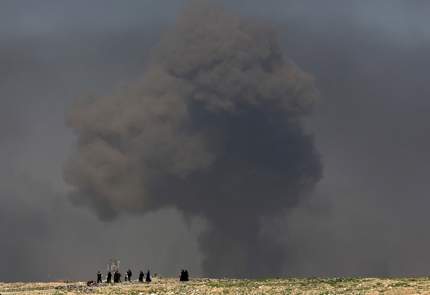 FILE - In this March 9, 2017 file photo, a large cloud of smoke rises during fighting between Iraqi security forces and Islamic State militants as civilians walk toward Iraqi security forces after fle ...