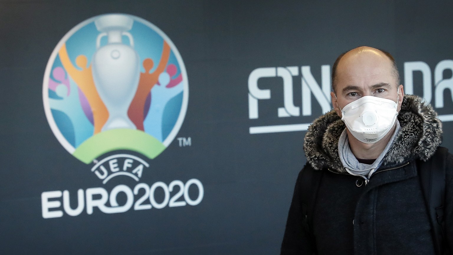 epa08301440 A passenger wearing a protective mask passes by a UEFA EURO 2020 banner at the arrivals terminal of Henri-Coanda International Airport, in Otopeni, 20 Km north from Bucharest, Romania, 17  ...