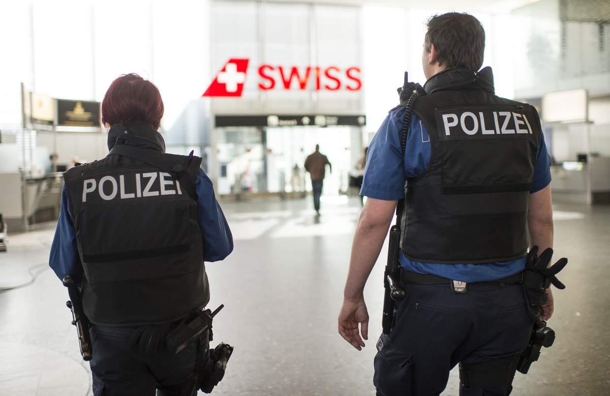 Police officers indicate their presence at the Airport of Zurich, in Zurich-Kloten, Switzerland, Tuesday, 22 March 2016. All flights to brussels are canceled and security measures have been raised fol ...