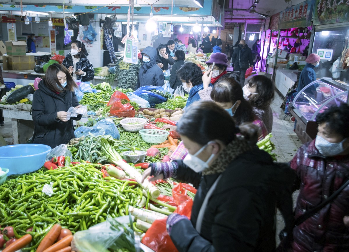 In this photo released by China's Xinhua News Agency, people shop for vegetables at a market in Wuhan in central China's Hubei Province, early Thursday, Jan. 23, 2020. China closed off a cit ...