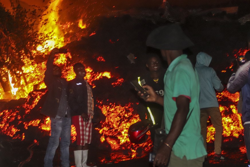 People stand and take selfies in front of lava from the eruption of Mount Nyiragongo, in Buhene, on the outskirts of Goma, Congo in the early hours of Sunday, May 23, 2021. Congo&#039;s Mount Nyiragon ...
