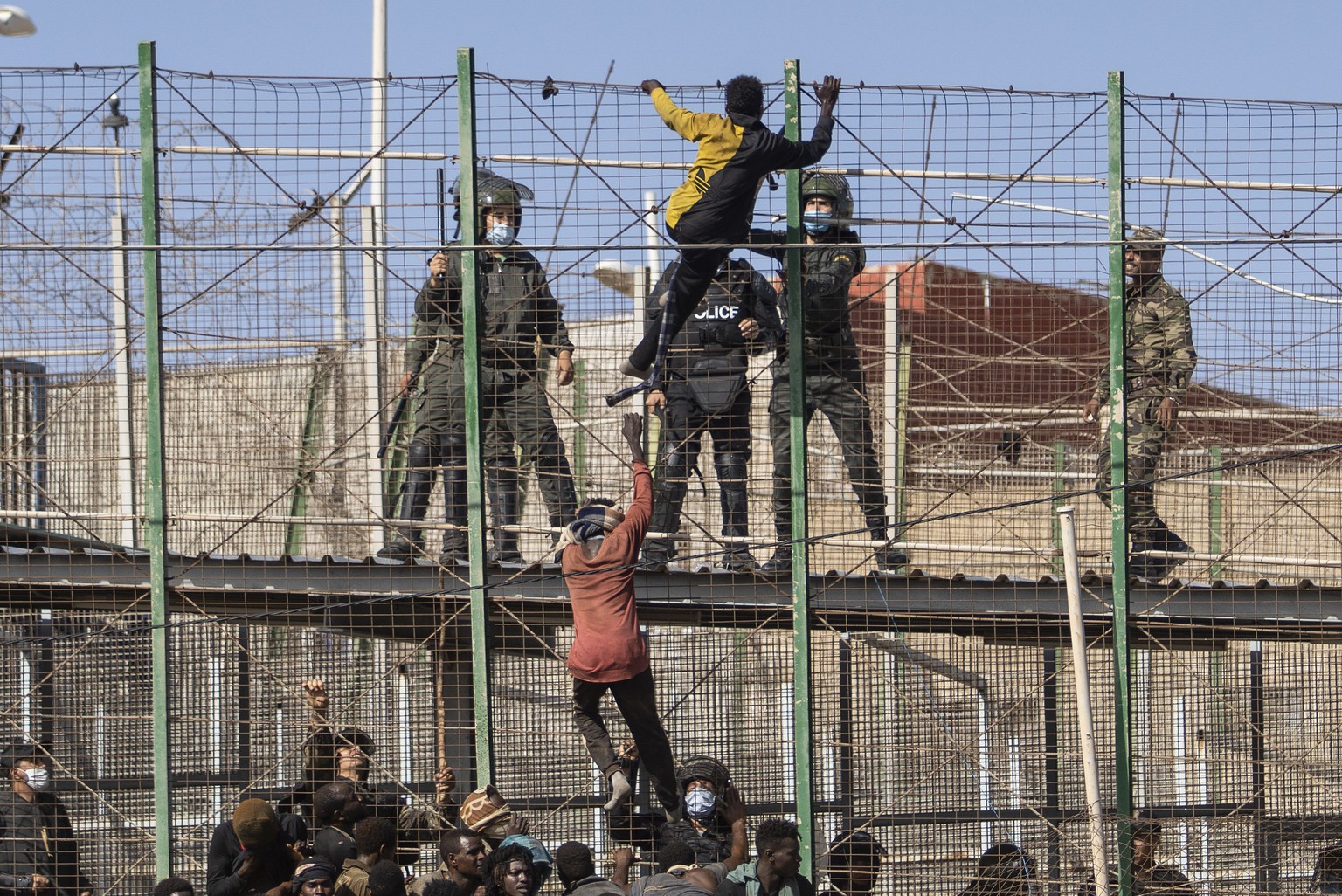 Migrants climb the fences separating the Spanish enclave of Melilla from Morocco in Melilla, Spain, Friday, June 24, 2022. Dozens of migrants stormed the border crossing between Morocco and the Spanis ...