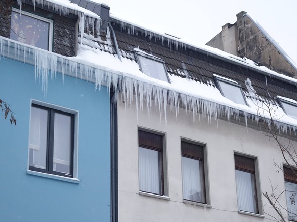 10.02. 2021 Dortmund , Eiszapfen haben sich an der Dachtraufe von H�usern gebildet. Gef�hrlich wird es f�r Fu�g�nger die unten auf dem B�rgersteig gehen. Hier muss mit einem Schild und einer Absperrun ...