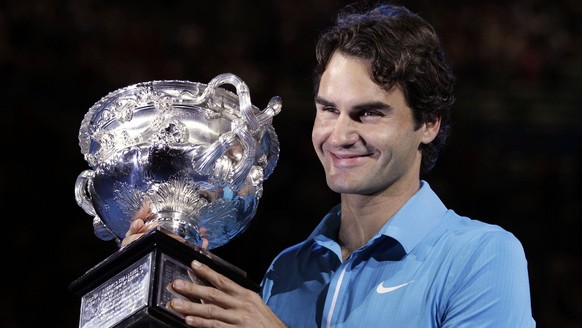 Roger Federer of Switzerland holds the trophy after beating Andy Murray of Britain to win the Men's singles final match at the Australian Open tennis championship in Melbourne, Australia, Sunday, ...