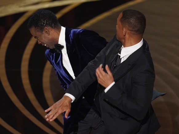 FILE - Will Smith, right, hits presenter Chris Rock on stage at the Oscars in Los Angeles on March 27, 2022, after Rock made a joke about his wife. Pinkett Smith turned her husband