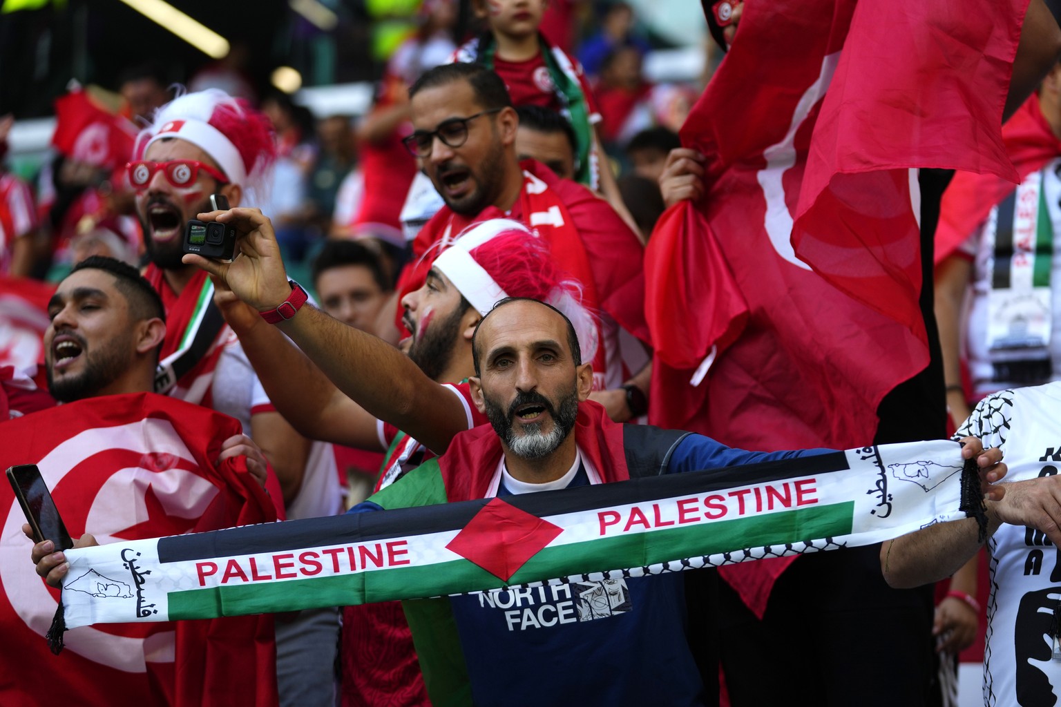 A fan shows a scarf reading &quot;Palestine&quot; before the start of the World Cup group D soccer match between Denmark and Tunisia, at the Education City Stadium in Al Rayyan , Qatar, Tuesday, Nov.  ...