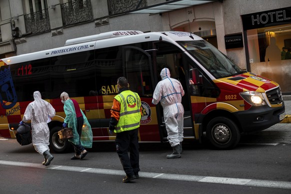 A patient, second left, is transferred to a medicalised hotel during the COVID-19 outbreak in Madrid, Spain, Tuesday, March 24, 2020. For most people, the new coronavirus causes only mild or moderate symptoms. For some it can cause a more serious illness. (AP Photo/Bernat Armangue)
