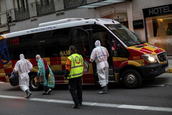 A patient, second left, is transferred to a medicalised hotel during the COVID-19 outbreak in Madrid, Spain, Tuesday, March 24, 2020. For most people, the new coronavirus causes only mild or moderate  ...