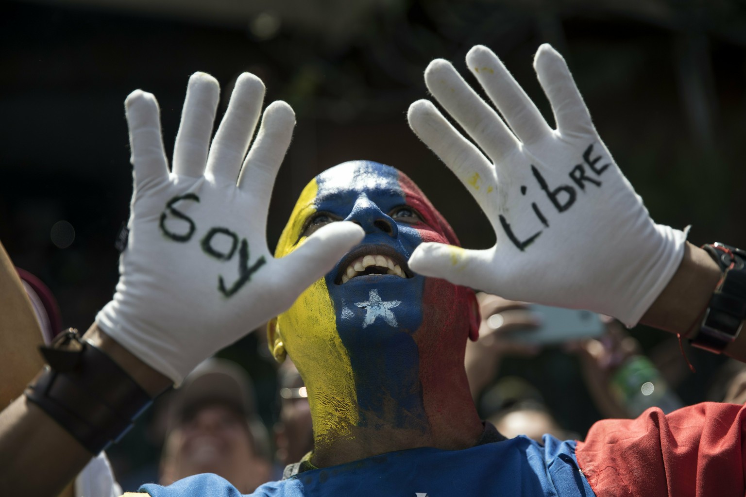 An anti-government protester, his face painted with Venezuela&#039;s national colors and the Spanish words for &quot;I am free&quot; written on his white-gloved hands, takes part in a demonstration de ...