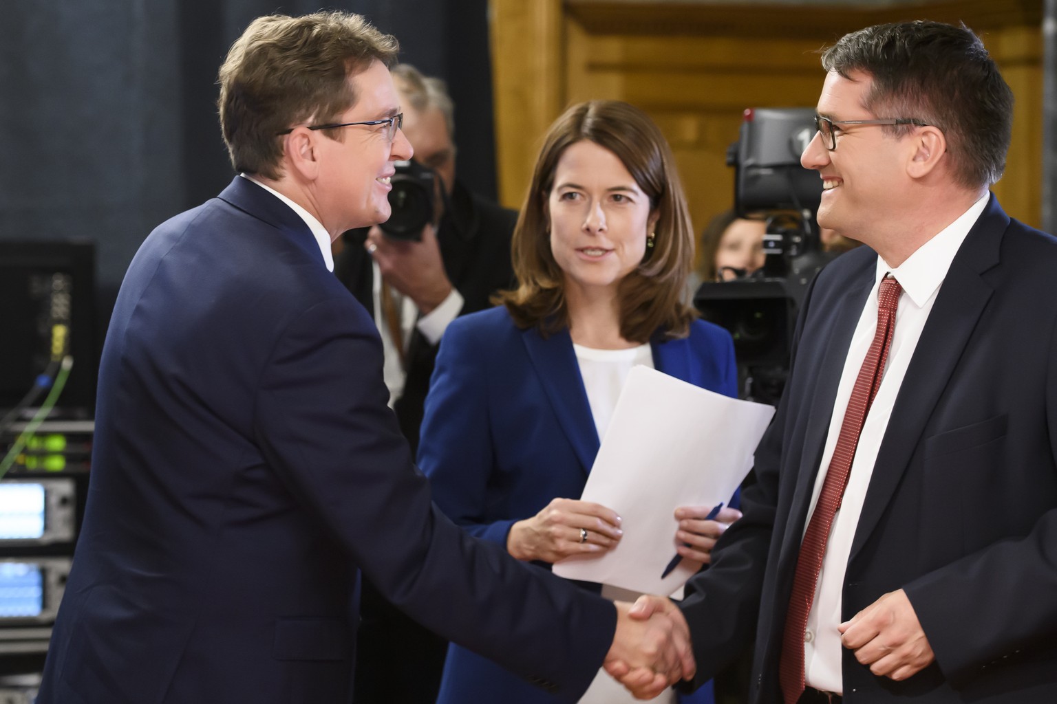 SVP-Parteipraesident und Nationalrat Albert Roesti, links, und SP-Parteipraesident und Staenderat Christian Levrat, rechts, geben sich die Hand, an der Seite von FDP-Parteipraesidentin und Nationalrae ...