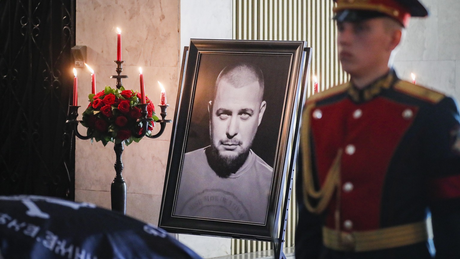 epa10564724 An honor guard soldier stands next to a portrait of Maxim Fomin, known by the pseudonym Vladlen Tatarsky, placed next to his coffin during a farewell ceremony at the Troekurovsky cemetery ...