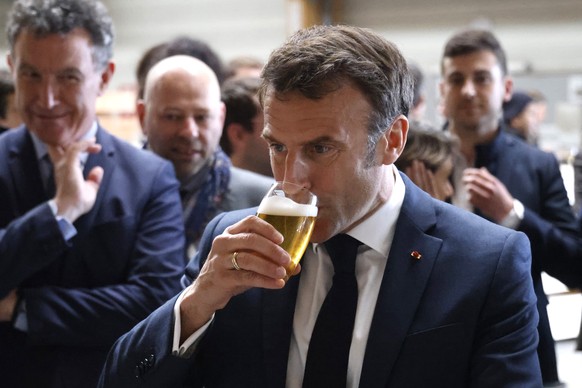 French President Emmanuel Macron drinks a beer during a visit to Mathis, a company specialized in large wooden buildings, in Muttersholtz, eastern France, Wednesday, April 19, 2023. (Ludovic Marin, Po ...