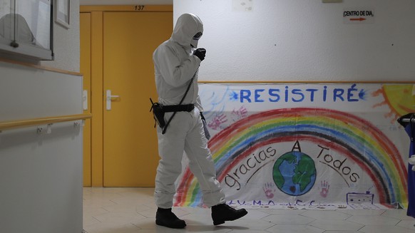 A member of the UME (Emergency Army Unit) wearing a wearing a protective suit to protect against coronavirus disinfects next to a banner reading in Spanish: &quot;I will resist, Thanks everybody&quot; ...