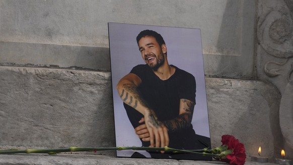 A photo of former One Direction singer Liam Payne is placed with a rose and candles as fans gather in Madrid, Spain, Sunday, Oct. 20, 2024, after the British pop singer fell to his death from a hotel  ...