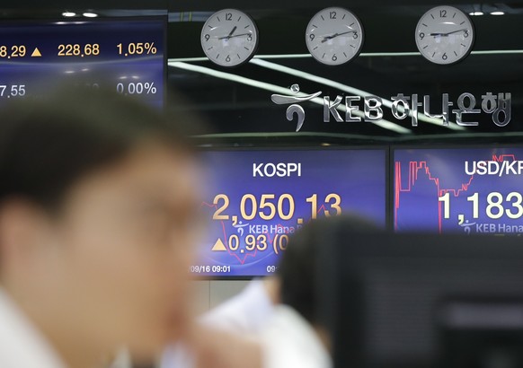 A currency trader watches the computer monitors near the screens showing the Korea Composite Stock Price Index (KOSPI), center, and the foreign exchange rate between U.S. dollar and South Korean won a ...