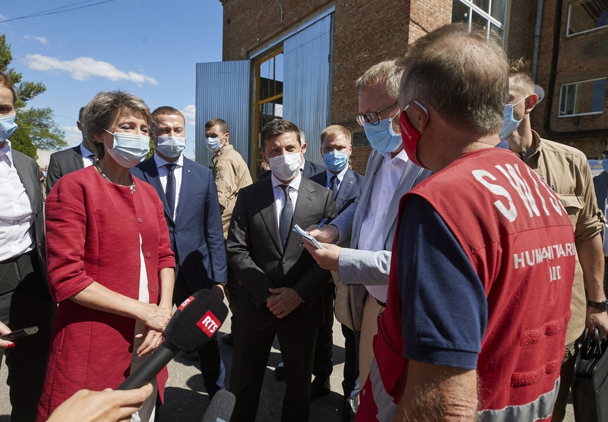 Swiss Federal President Simonetta Sommaruga, left, talks to a Swiss humanitarian aid representative while Ukrainian President Volodymyr Zelenskiy, looks on, center, during a visit to a water pumping s ...