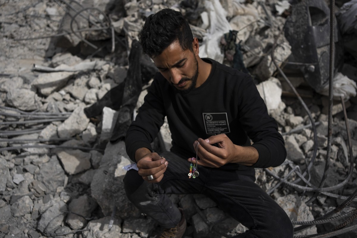 Ibrahim Hasouna, center, the sole survivor among his family, sits amidst the debris of his bombed home in Rafah, southern Gaza Strip, Tuesday, Feb. 13, 2024. On Monday, February 12, Hasouna lost eight ...