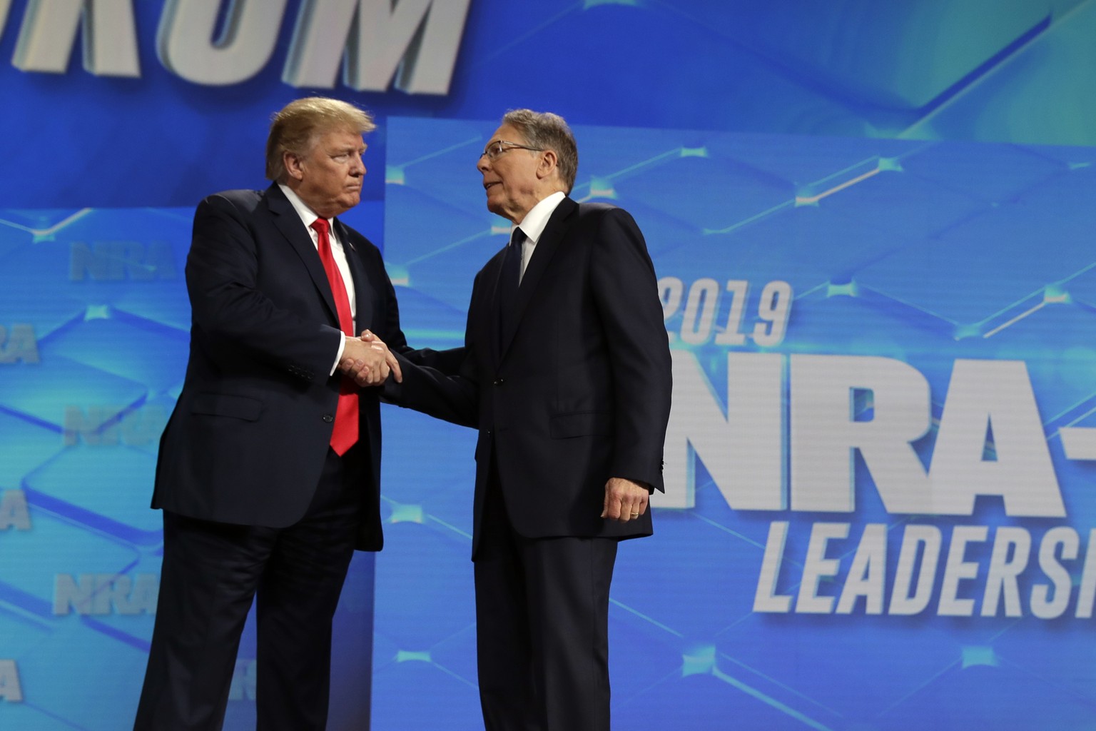 President Donald Trump shakes hands with NRA executive vice president and CEO Wayne LaPierre, has he arrives to speak to the annual meeting of the National Rifle Association, Friday, April 26, 2019, i ...