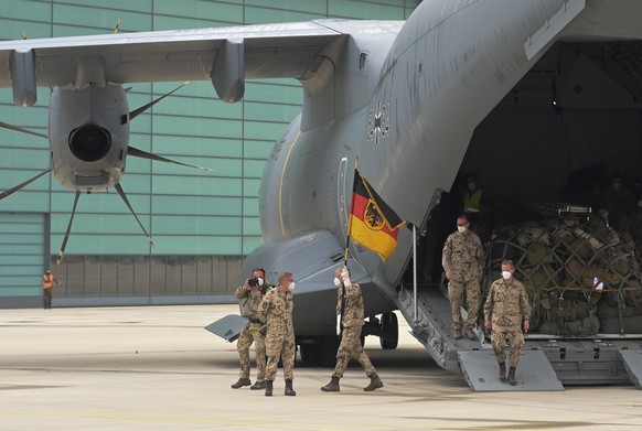epa09313116 Soldiers of the German Bundeswehr disembark with their troop flag from an Airbus A400M transport aircraft of the German Air Force on the tarmac at the Wunstorf air base, Germany, 30 June 2 ...