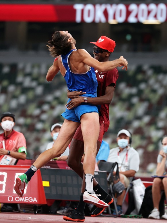 epa09385577 Gold Medalists Gianmarco Tamberi of Italy (L) and Essa Mutaz Barshim of Qatar (R) react after the Men&#039;s High Jump Final during the Athletics events of the Tokyo 2020 Olympic Games at  ...