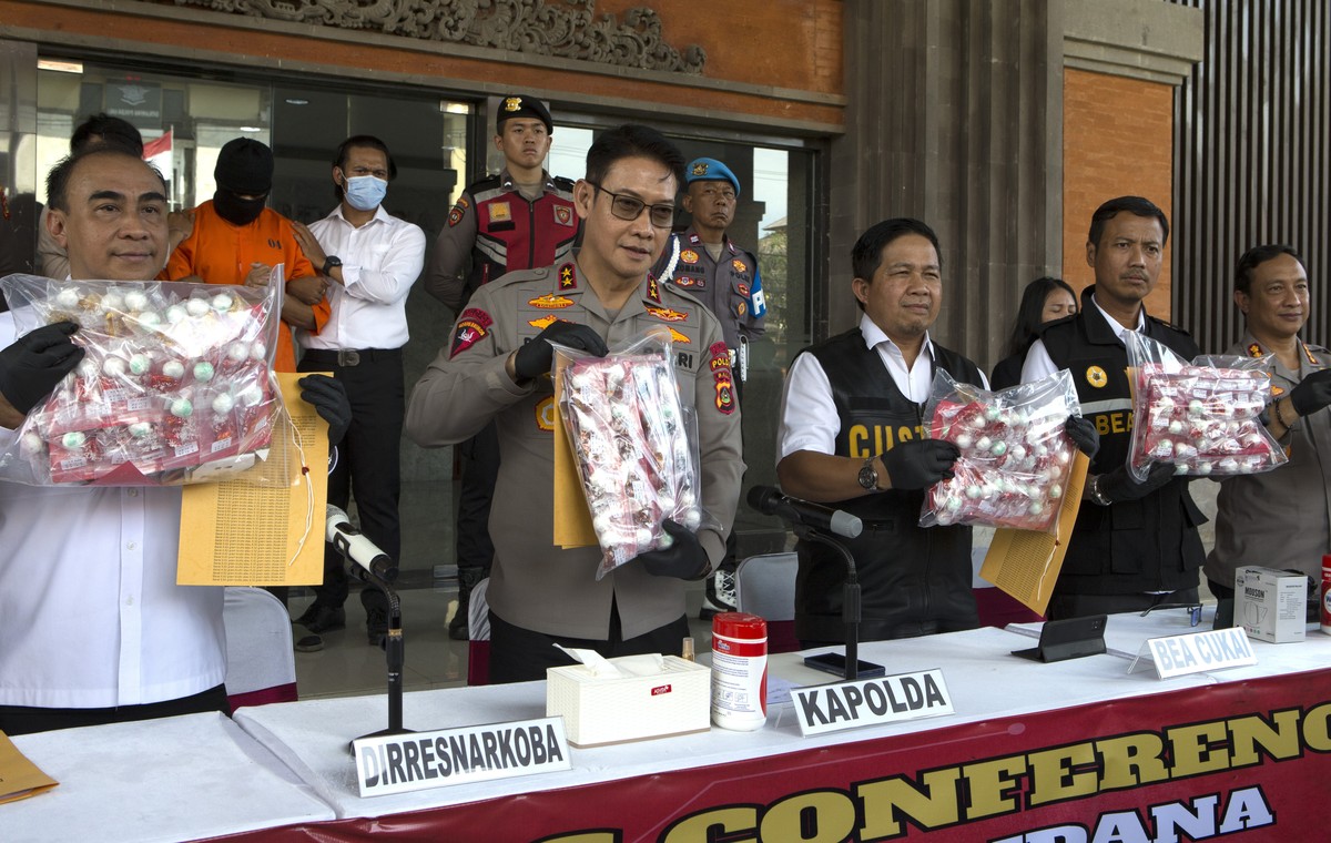Authorities hold a news conference as an Australian man, second left in the background, arrested for allegedly smuggling cocaine stands at the police headquarters in Bali, Indonesia, Monday, May 26, 2 ...