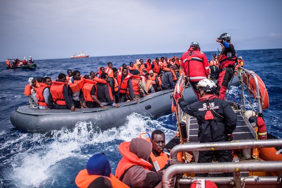 epa07080425 Refugees on a rubber dinghy are rescued by members of the NGO 'SOS Mediterranee' from the 'Aquarius' vessel during an operation to rescue migrants, about 50 kilometers ...