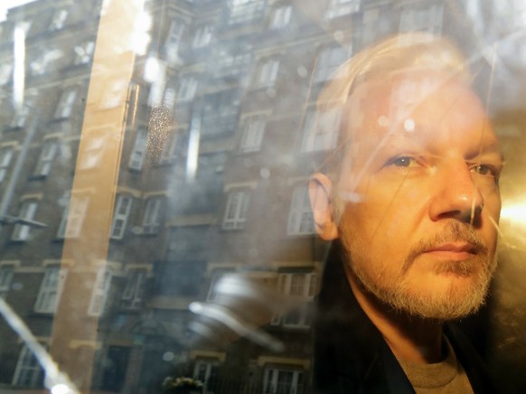 FILE - In this May 1, 2019 file photo buildings are reflected in the window as WikiLeaks founder Julian Assange is taken from court, where he appeared on charges of jumping British bail seven years ag ...