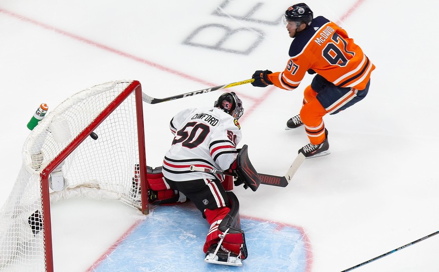 Edmonton Oilers&#039; Connor McDavid (97) scores against Chicago Blackhawks goaltender Corey Crawford (50) during first-period NHL hockey Stanley Cup qualifying round game action in Edmonton, Alberta, ...