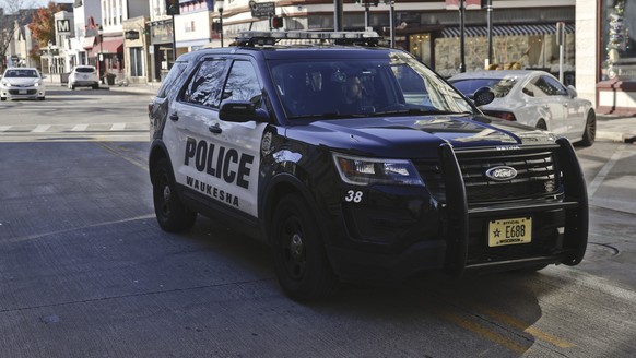 epa09598059 A police vehicle drives down Main Street with markings where evidence was collected and the location of a Christmas parade, reopens to the public in Waukesha, Wisconsin, USA, 22 November 2 ...