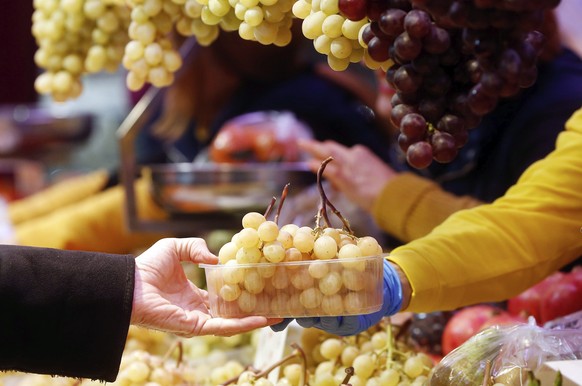 epa05690655 A greengrocer sells grapes at the Central Market in Valencia, Spain, 29 December 2016, as consumers prepare for the New Year&#039;s celebrations. Grapes are sold all over the country to we ...