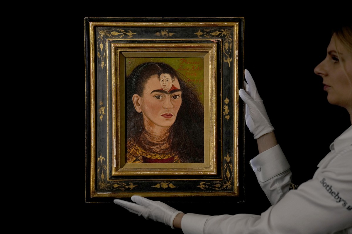 FILE - A staff member poses for photographs with the Mexican painter Frida Kahlo's 1949 self-portrait "Diego y yo", Diego and I, at Sotheby's auction house in London, Thursday, Oct ...