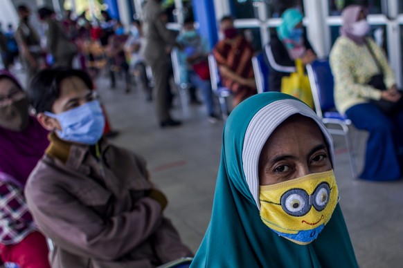 epa08374607 A woman wears a mask as she waits for her turn to buy food amid the coronavirus outbreak in Surabaya, East Java, Indonesia, 21 April 2020. Countries around the world are taking increased m ...