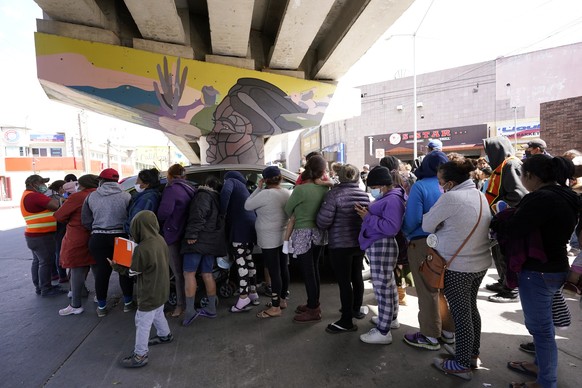 People surround a car as it arrives carrying food donations at a makeshift camp for migrants seeking asylum in the United States at the border crossing Friday, March 12, 2021, in Tijuana, Mexico. The  ...