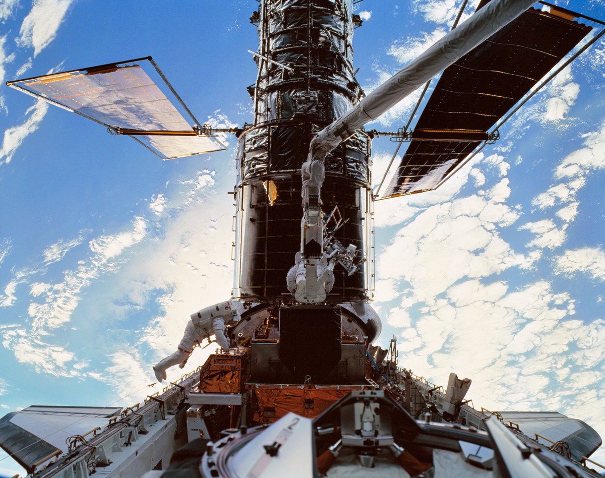 STS103-501-026 19 - 27 December 1999 --- Astronauts C. Michael Foale, left, and Claude Nicollier on Discovery s robotic arm install a Fine Guidance Sensor FGS into a protective enclosure in the Shuttl ...