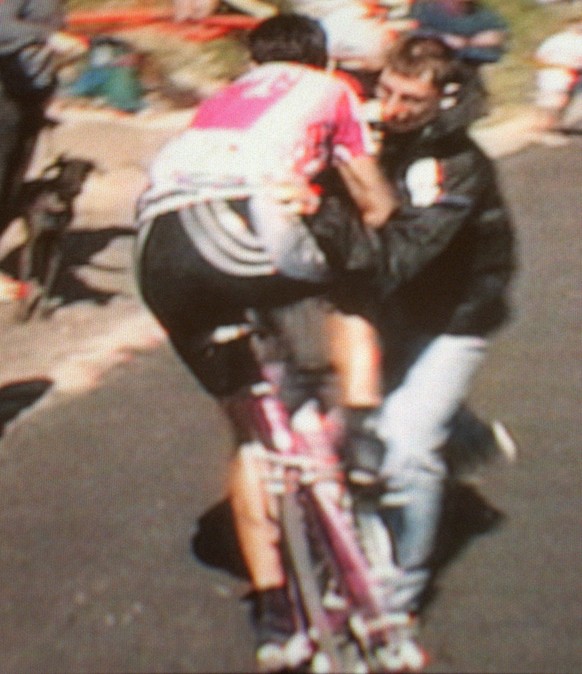 Italian rider Giuseppe Guerini falls to the road with a spectator, at right, who was taking a photo of him just over a kilometer from the finish line of the Tour de France cycling race in Alpe d' ...