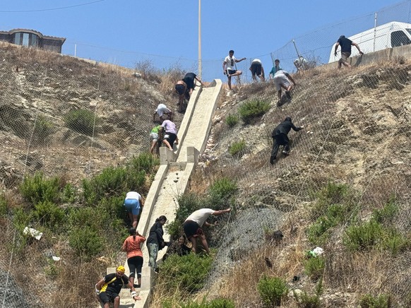 Hundreds of people are swimming across to Ceuta from Morocco, with a crowd waiting on the other side of the border. Several migrants, on July 30, 2026, in Ceuta, Spain. Hundreds of people of Maghreb o ...